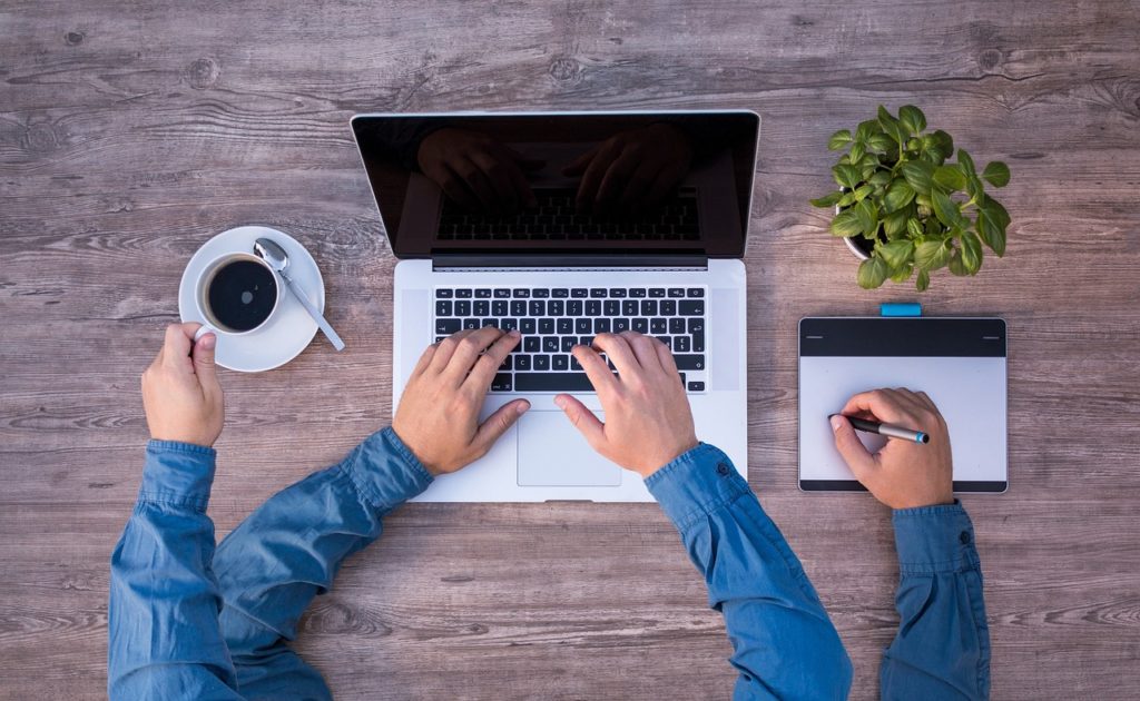 office person multitasking on desk laptop coffee tablet device