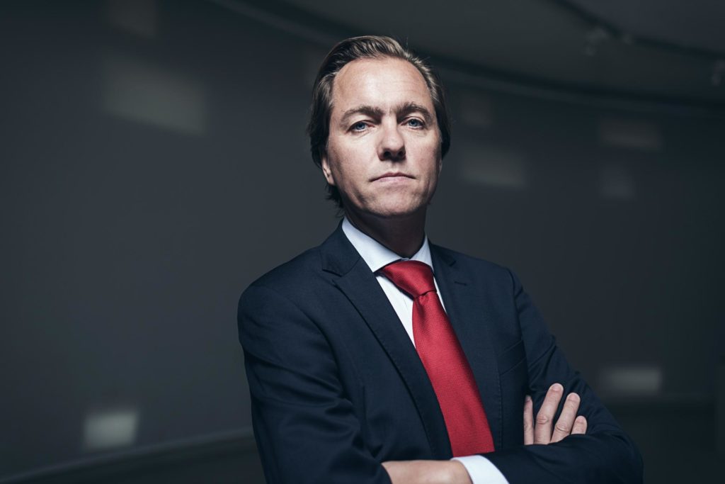 Serious confident businessman with red tie in room. Looking in camera.