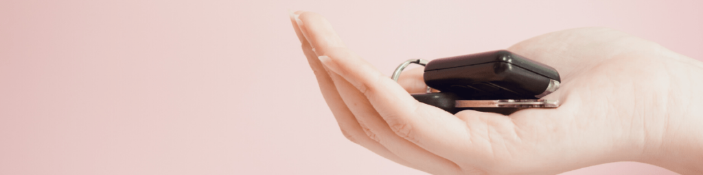 asian woman holding car key by right hand with pink pastel background
