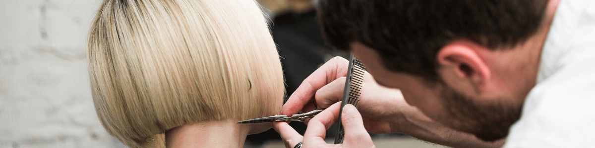 male-hairdresser-cutting-female-client-s-hair-in-salon-with-scissors