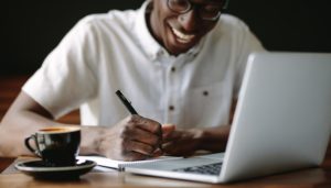 man-writing-notes-sitting-at-a-coffee-shop