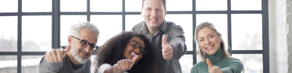 happy-team-with-laptop-showing-thumb-up-gesture