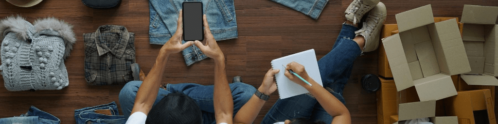selling-online-ideas-concept-small-business-owner-top-view-men-and-women-taking-photo-to-shirts-with-cell-telephone-or-smartphone-digital-camera-on-wooden-floor-with-postal-parcel-box