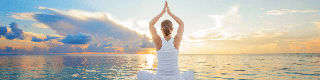 caucasian-woman-practicing-yoga-at-seashore