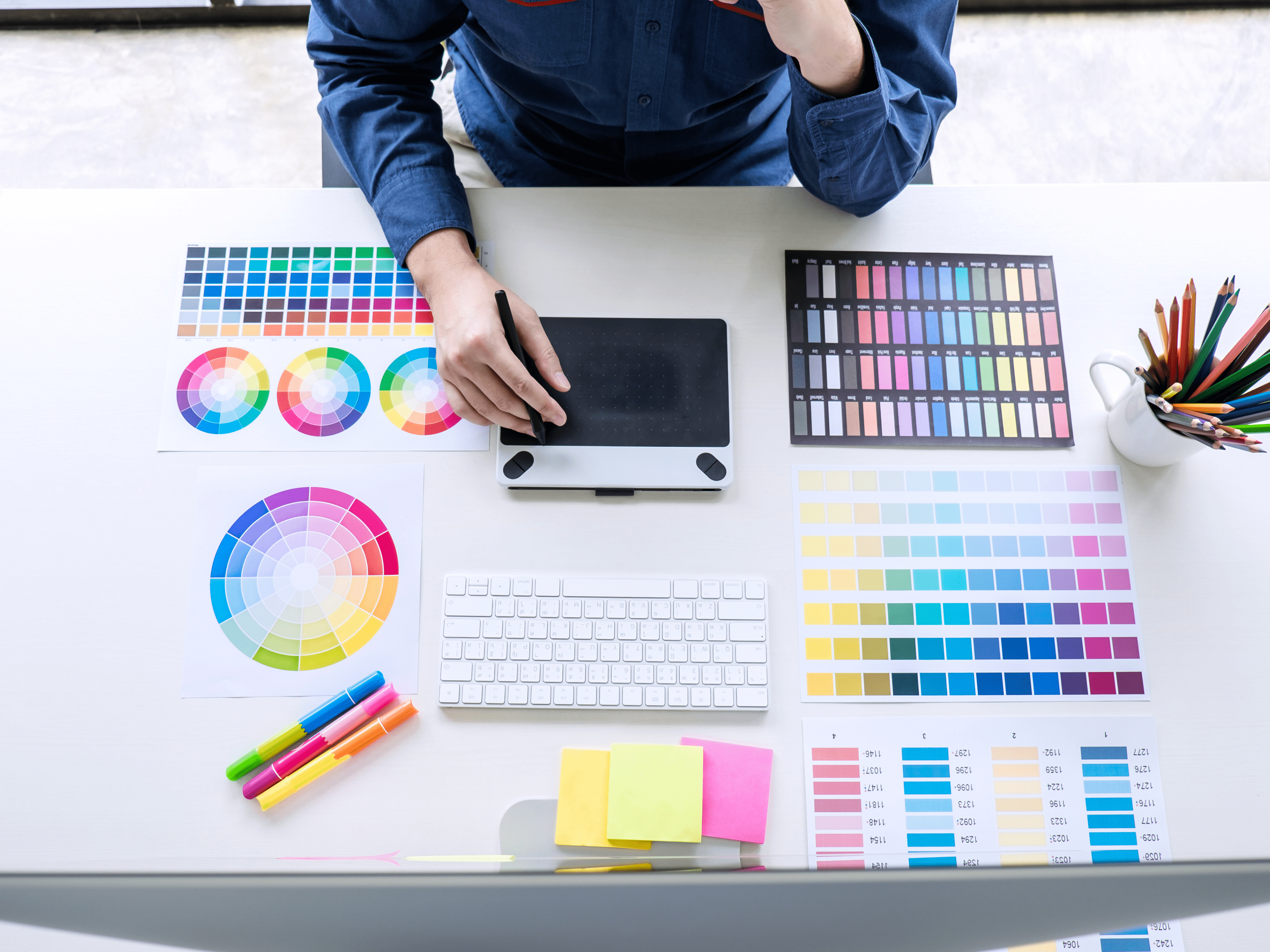 image-of-male-creative-graphic-designer-working-on-color-selection-and-drawing-on-graphics-tablet-at-workplace-with-work-tools-and-accessories-top-view-workspace