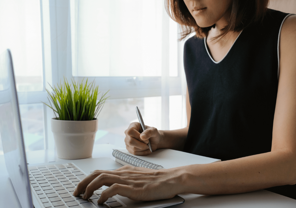 woman-writing-and-using-a-laptop