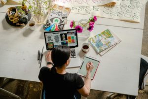 photo-of-woman-writing-on-tablet-computer-while-using-laptop