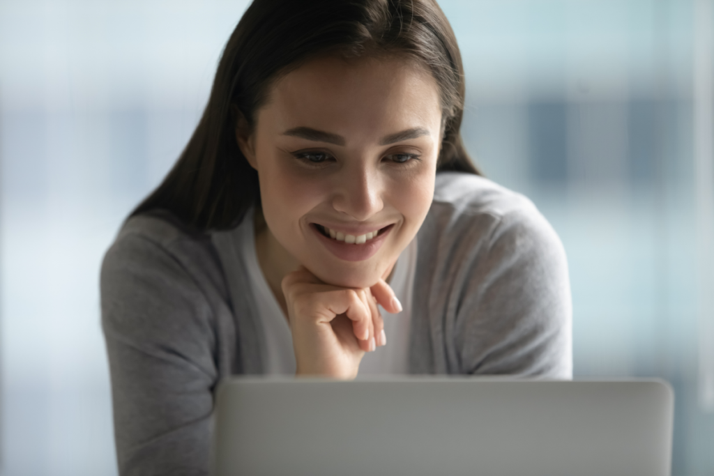 woman smiles in front of laptop