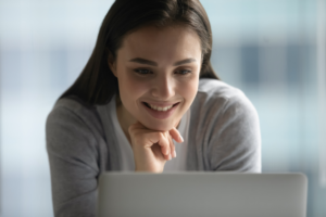 woman smiles in front of laptop