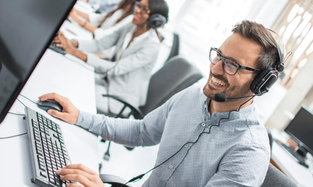 smiling-young-sales-representative-man-with-headset-using-computer-performing-his-job-in-communication