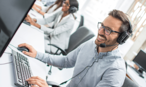 smiling-young-sales-representative-man-with-headset-using-computer-performing-his-job-in-communication
