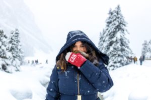 woman in blue zip up hooded jacket standing in snow
