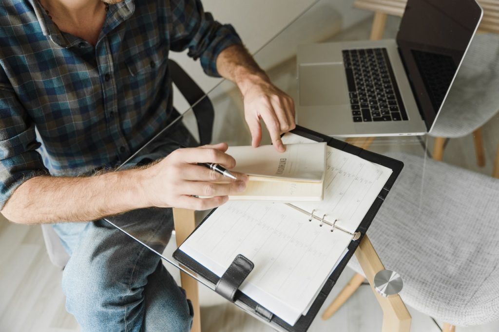 male applicant in blue and white plaid long sleeve shirt writing on white paper