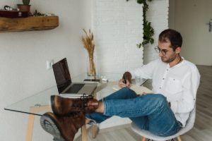 man in white dress shirt and blue denim jeans sitting on wooden chair and writing his long term career plan