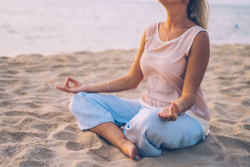 blonde woman meditating by the beach