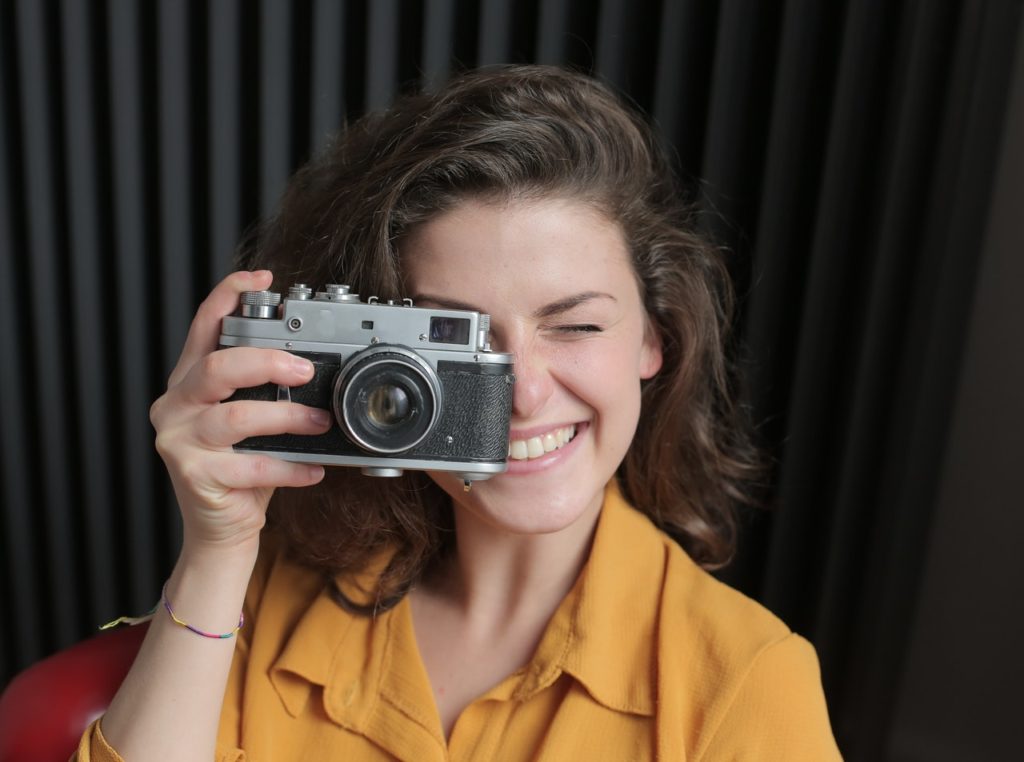 woman in yellow shirt holding gray and black camera