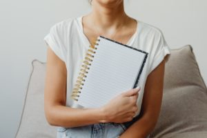 woman holding a blank self care journal