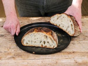 baker with sourdough bread on plate