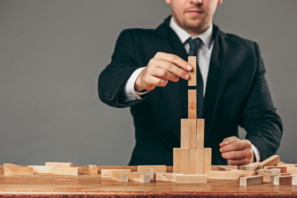 Man and wooden cubes on table management concept