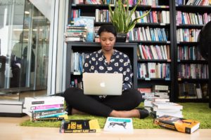 Woman sitting down surrounded by books