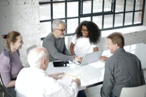 Group of multiracial coworkers gathering around table with gadgets and documents in modern workspace