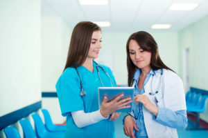 doctor showing digital tablet results to medical assistant