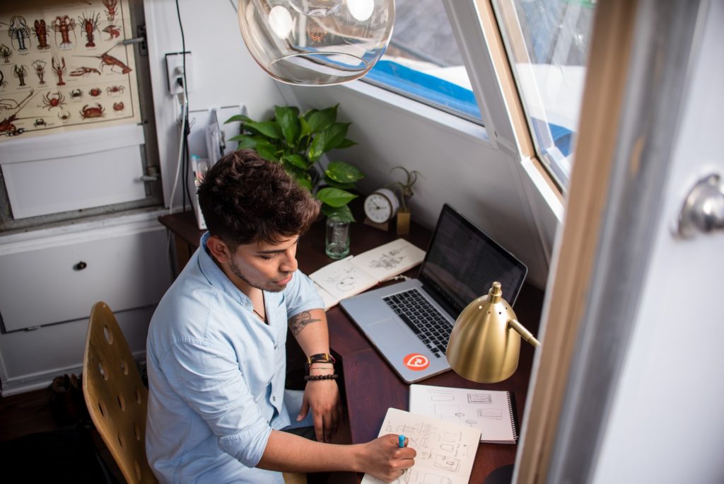 freelancer sits while writing in front of macbook