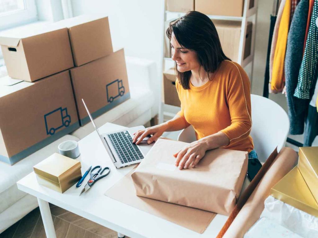 Small Business Owner Typing On Laptop Packing an Order