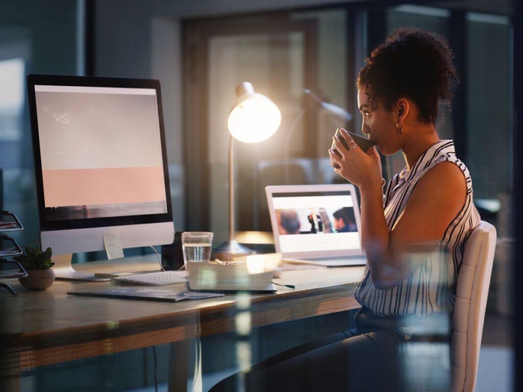 business woman sipping on coffee while working on her side hustle