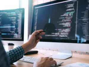 web developer holds pen pointing at code