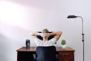 man holding his head while sitting on chair near computer desk