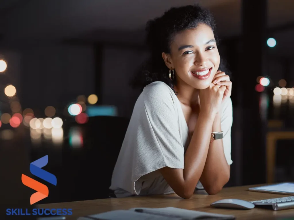 A woman smiles at her laptop, seated at a desk, embracing a career change at 35 with optimism and determination