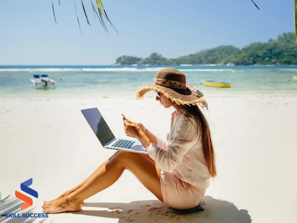 A woman working on a laptop while sitting on the beach, embodying the freelance lifestyle of a Fiverr professional