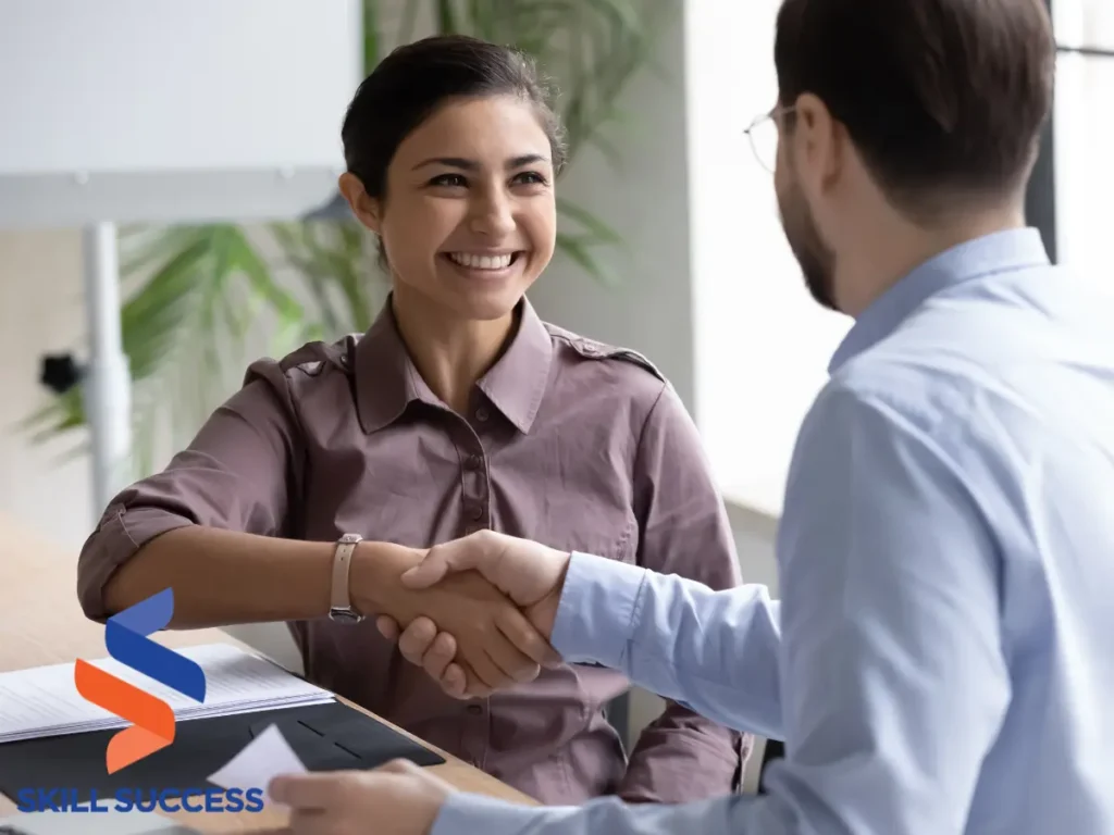 A man and woman shaking hands at a desk, symbolizing successful recruitment strategies