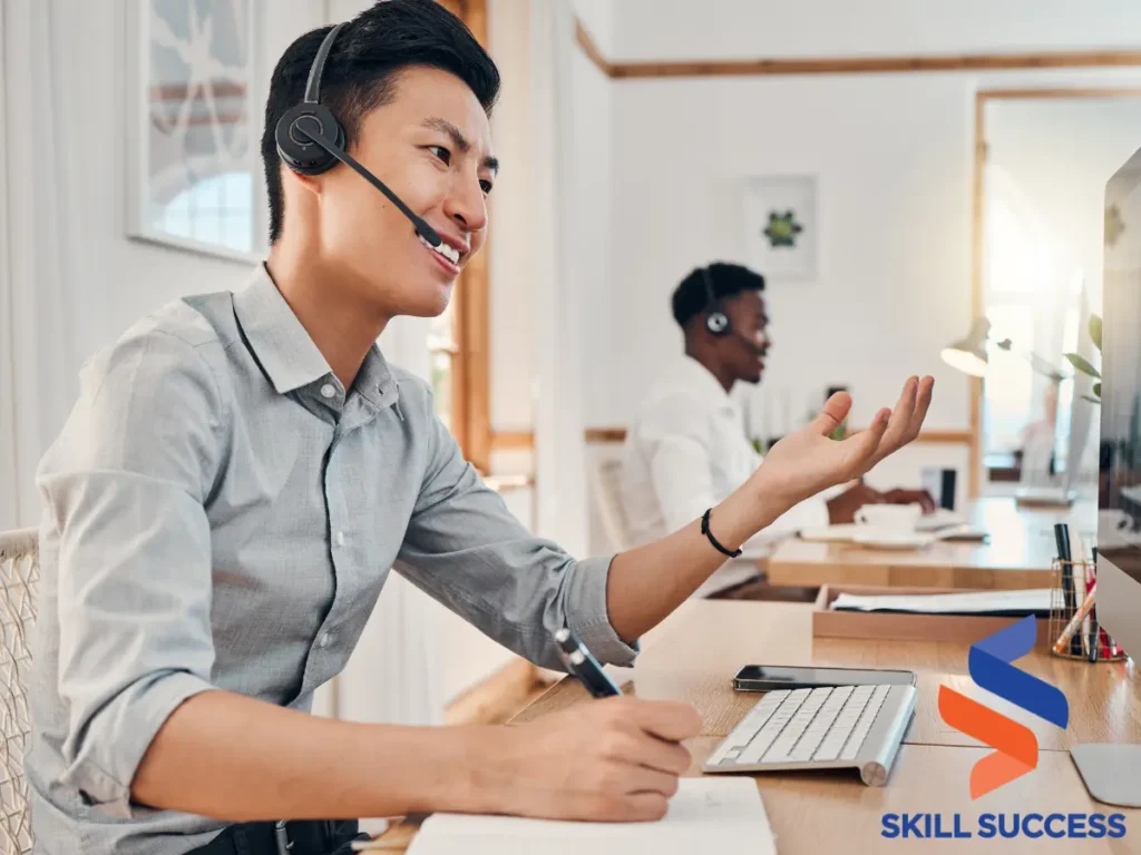 A man wearing a headset and sitting at a desk with a computer, preparing sales calls scripts.