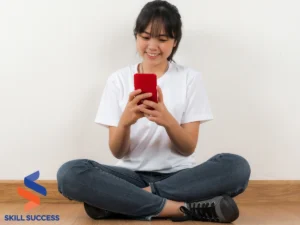 A woman seated on the floor, engaged with her cell phone, exploring microlearning myths through digital content