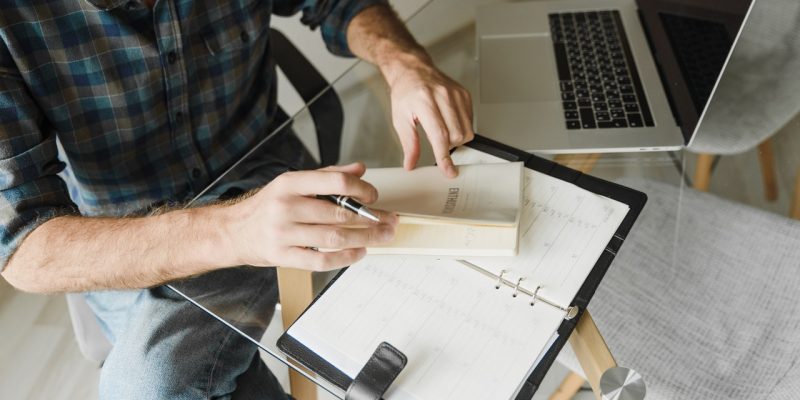 male applicant preparing resume male applicant in blue and white plaid long sleeve shirt writing on white paper