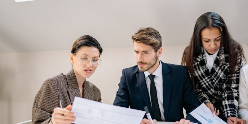 three people looking over printouts on table