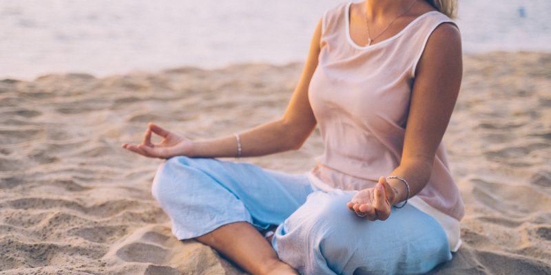 blonde woman meditating by the beach
