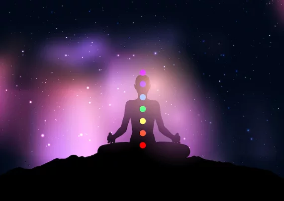 Silhouette of a female with chakra in yoga pose against starry night sky