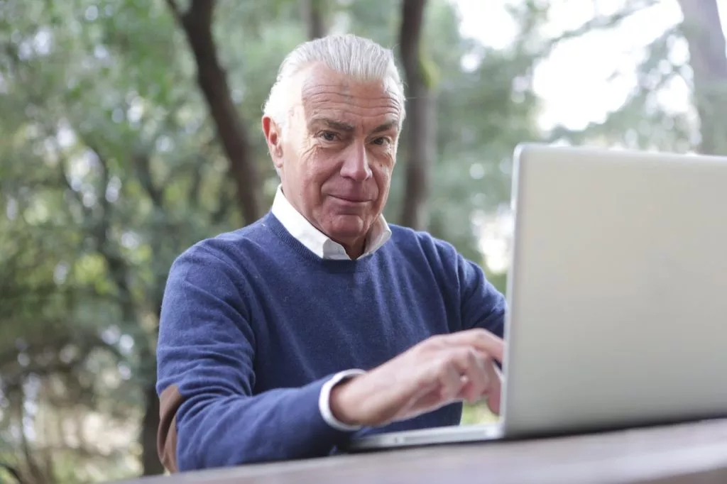 man typing on laptop working on new career at 50
