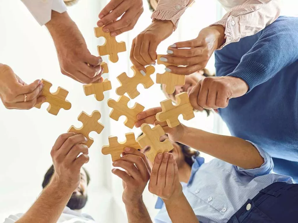 Team Collaboration Members Holding Pieces of Wooden Puzzles