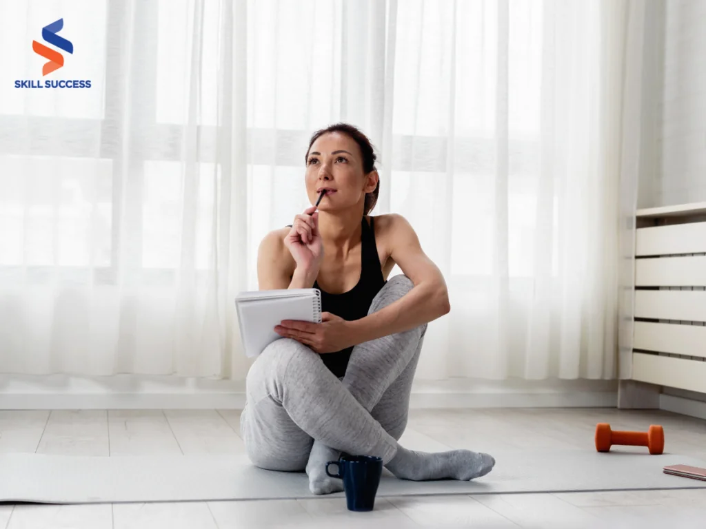 A woman sits on the floor with a book and a dumbbell, symbolizing personal growth through reading and physical exercise.