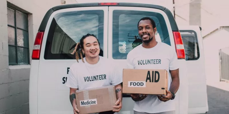 Two male nonprofit organization volunteers holding boxes