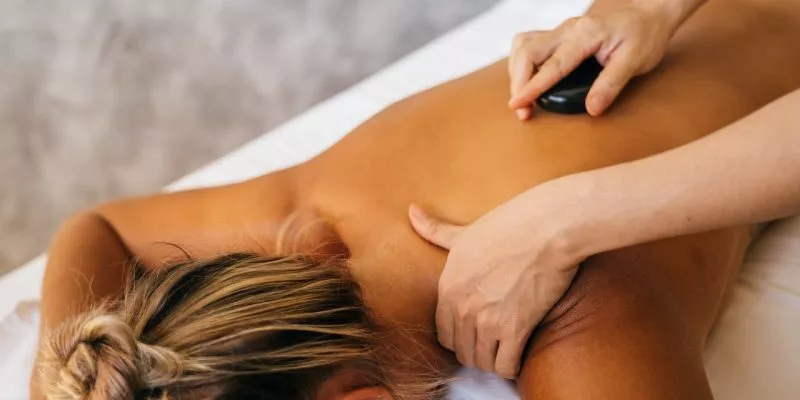 person massaging a client with a stone