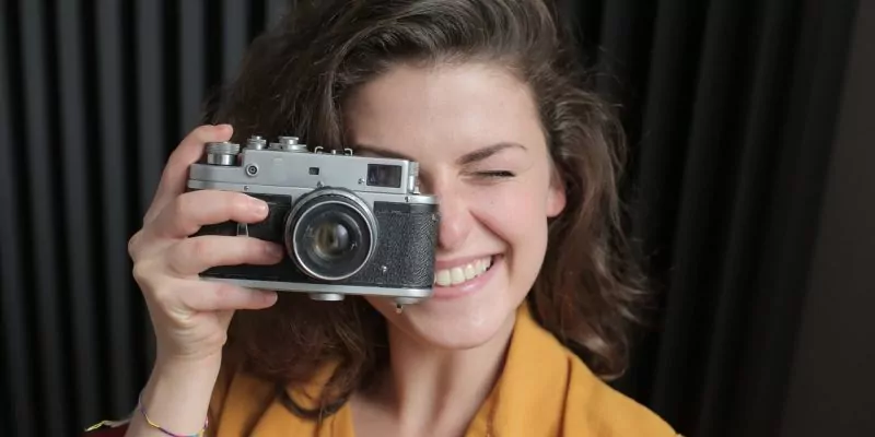 woman in yellow shirt holding gray and black camera