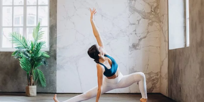 woman in blue sports bra and white leggings doing kundalini yoga