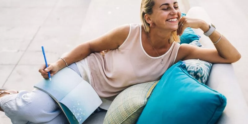 woman in white tank top sitting on gray couch