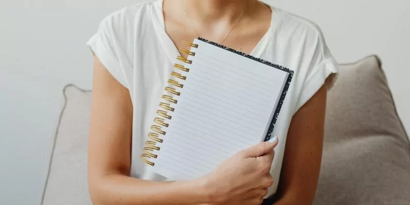 woman holding a blank self care journal